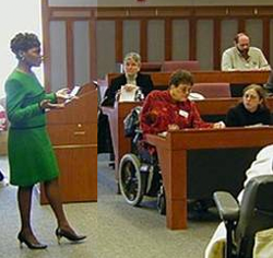 Photo showing lecturer with audience that includes person in wheelchair