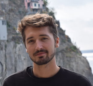 Man standing at vacation spot with cliff houses in background