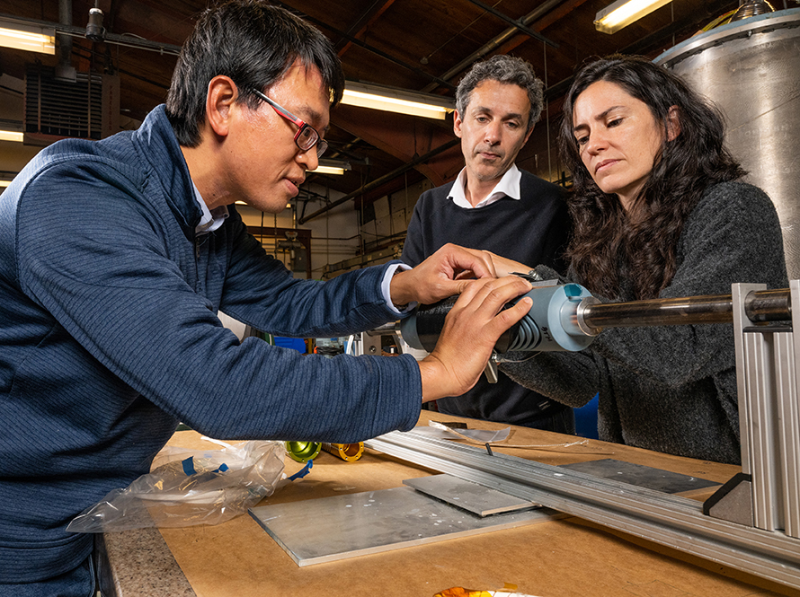 L-R: Researchers Tengming Chen, Paolo Ferracin, and Laura Garcia Fajardo examine the windings of a superconducting magnet