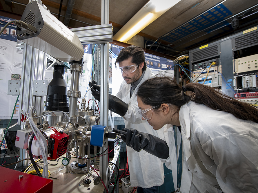 Two scientists adjust equipment at the Associated Particle Imaging (API) Test Stand