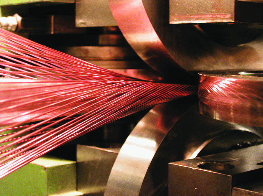 Machining head forms and compresses strands of superconducting wire into a hard flat cable