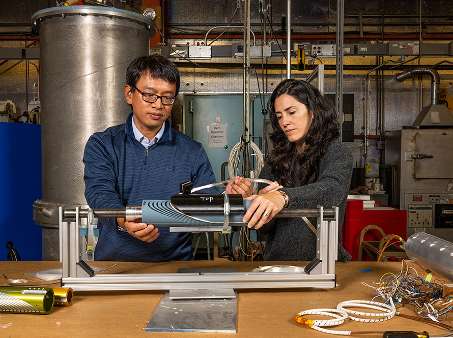 Two researchers at a workbench examine a superconducting magnet winding