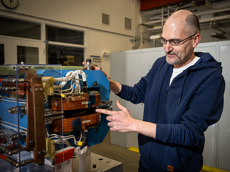 Researcher examines a blue electromagnet for the ALS Upgrade