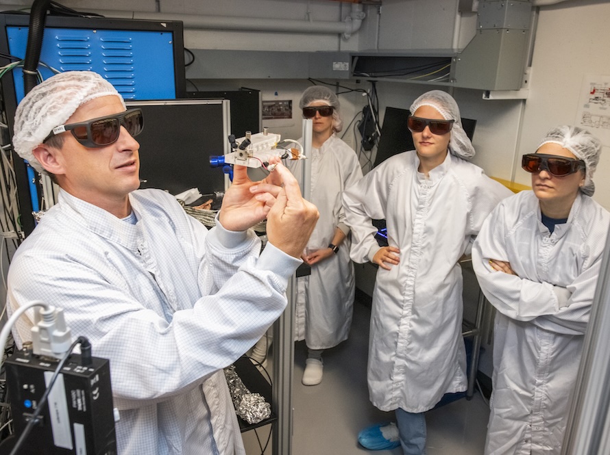 Scientists and tour group visitors, gowned and goggled for a laser area