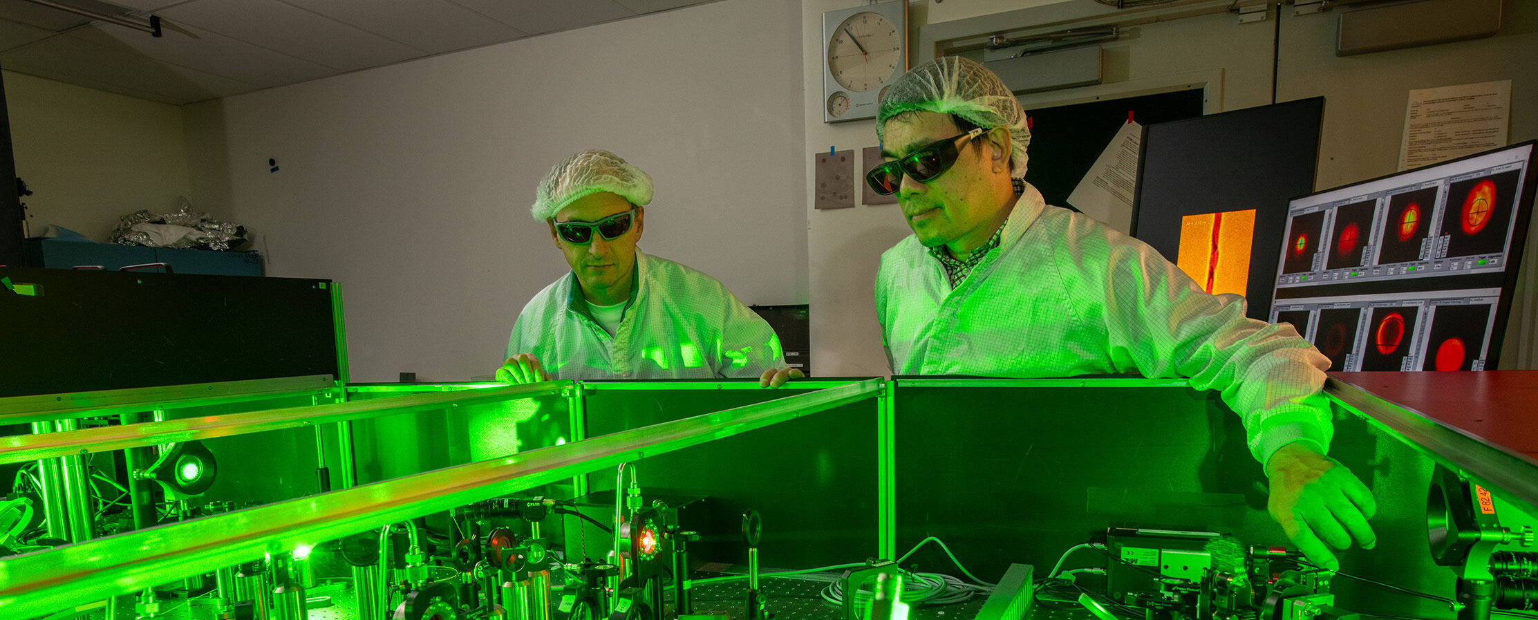 Physicist Research Scientist Hai-En Tsai (right) and Physicist Senior Scientist/Engineer Jeroen van Tilborg make adjustments in the Berkeley Lab Laser Accelerator (BELLA) at Lawrence Berkeley National Laboratory (Berkeley Lab), 12/18/2025. The researchers used X-rays and electrons to make a video of a shockwave moving through water, which has potential to impact fusion energy research. The green light seen here is produced by one of BELLA’s lasers.